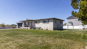 Back of house with brick siding, a yard, an attached garage, and fence
