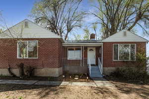 View of front featuring a chimney, brick siding, and a porch.