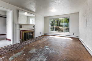 Unfurnished living room featuring a textured wall, a glass covered fireplace, a textured ceiling, and a baseboard radiator