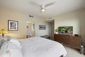 Bedroom featuring light carpet, connected bathroom, and ceiling fan