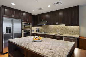 Kitchen featuring under cabinet range hood, stainless steel appliances