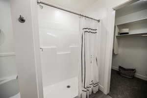 Full bath featuring a shower stall and baseboards