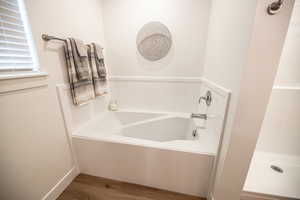 Bathroom featuring wood finished floors and a garden tub