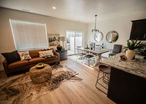 Living room featuring recessed lighting, a notable chandelier, visible vents, and light wood-style flooring