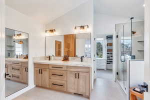 Bathroom featuring a shower stall, tile patterned flooring, double vanity, a healthy amount of sunlight, and a sink