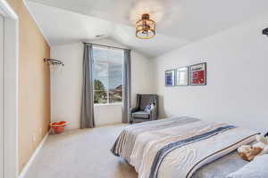Bedroom featuring vaulted ceiling, carpet floors, and baseboards