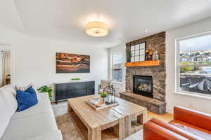 Living area featuring a stone fireplace, a wealth of natural light, light wood finished floors, and baseboards