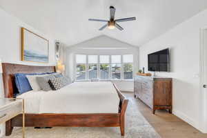 Bedroom with light wood-style floors, vaulted ceiling, a ceiling fan, and baseboards