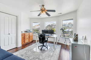 Office area with ceiling fan, baseboards, dark wood-style flooring, and visible vents