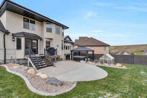 Back of house featuring fence, stucco siding, a patio area, a lawn, and a gazebo