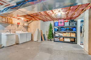 Unfinished below grade area with washing machine and dryer and a sink