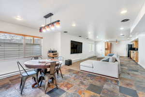 Dining area featuring stone tile floors, baseboards, recessed lighting, and a baseboard radiator