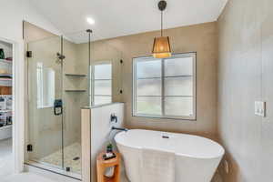 Bathroom with tile walls, a freestanding tub, and a stall shower