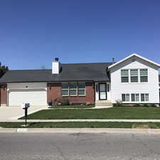 Tri-level home with concrete driveway, a chimney, an attached garage, a front yard, and brick siding