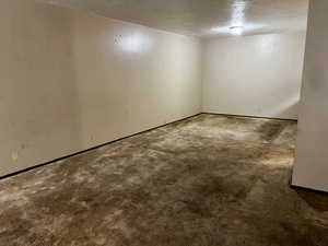Empty room featuring baseboards, carpet flooring, and a textured ceiling