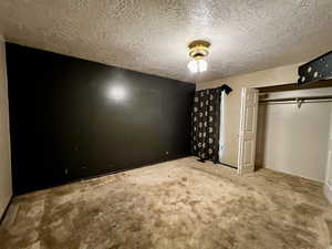 Unfurnished bedroom with carpet floors and a textured ceiling