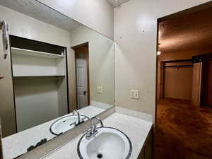 Bathroom featuring a spacious closet, vanity, and a textured ceiling