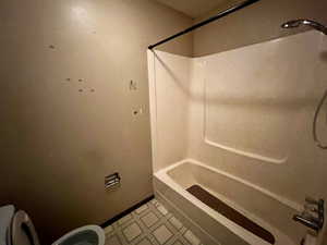 Full bathroom with toilet, tile patterned floors, and  shower combination