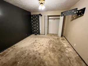 Unfurnished bedroom featuring carpet, a textured ceiling, and a closet