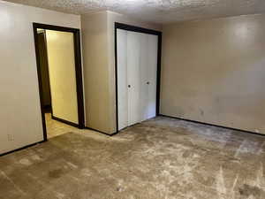Unfurnished bedroom featuring carpet, a textured ceiling, and a closet