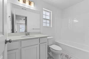 Full bath featuring washtub / shower combination, marble finish floor, visible vents, toilet, and vanity