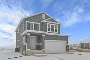 View of front of house featuring concrete driveway, brick siding, stucco siding, and a garage