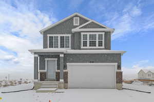 View of front of property with stucco siding, concrete driveway, brick siding, and a garage