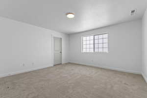 Unfurnished room with baseboards, visible vents, carpet, and a textured ceiling