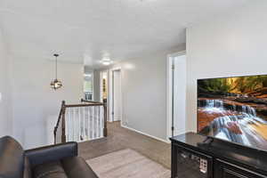 Living room with baseboards, carpet flooring, and a textured ceiling