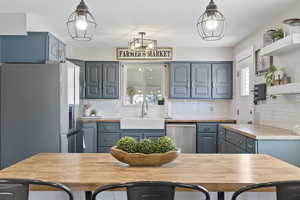 Kitchen featuring blue cabinets, stainless steel appliances, wood counters, and a sink