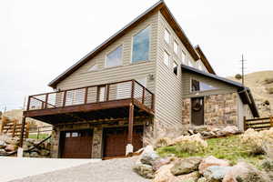 Exterior space front of home  with a garage, stone siding, fence, and a deck