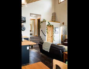 Living room with high vaulted ceiling, stairway, to sun room, laundry room, and exterior door to side yard. and LVT finished floors