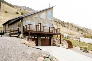 View of property exterior with stairway, fence, concrete driveway, an attached garage, and stone siding