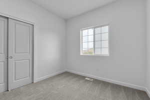 Unfurnished bedroom with visible vents, baseboards, carpet, and a closet