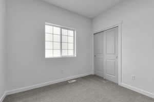 Unfurnished bedroom with carpet floors, a closet, visible vents, and baseboards