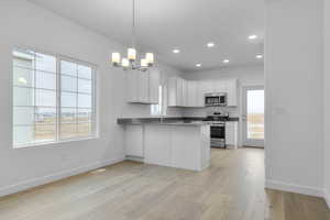 Kitchen featuring a peninsula, a notable chandelier, stainless steel appliances, and baseboards