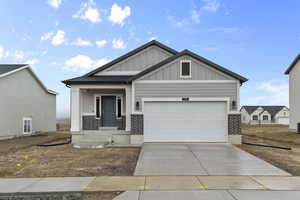 Craftsman-style house with board and batten siding, an attached garage, brick siding, and concrete driveway