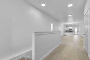 Corridor with baseboards, light wood-style flooring, and recessed lighting