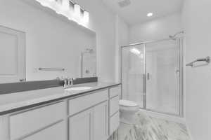 Bathroom with a shower stall, toilet, vanity, and visible vents