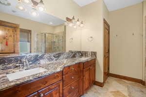 Master Bathroom featuring double vanity, tile patterned flooring, a stall shower, and a sink