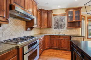 Kitchen , stainless steel appliances, a sink, light wood-type flooring, and glass insert cabinets
