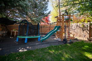 View of jungle gym with a yard, a fenced backyard, and a trampoline