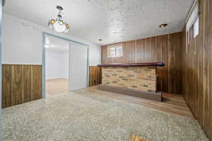 Bar with wooden walls, carpet floors, a wainscoted wall, and a textured ceiling