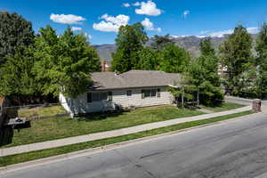 View of front of home with fence, a mountain view, and a front lawn
