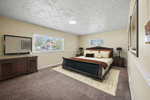 Carpeted bedroom featuring a textured ceiling and baseboards