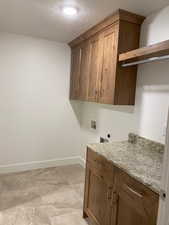 Laundry room with electric dryer hookup, cabinet space, hookup for a washing machine, and baseboards