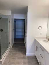 Bathroom with baseboards, vanity, a textured ceiling, and a stall shower