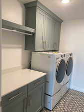 Clothes washing area featuring washing machine and dryer, baseboards, cabinet space, and a textured ceiling