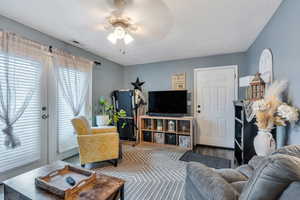 Living area with visible vents, wood finished floors, and ceiling fan