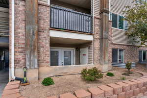 Property entrance featuring brick siding, french doors, and a balcony